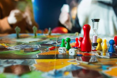 Masa oyunu kavramı - Yönetim Kurulu oyunu alan, birçok rakamlar, meeple, zar, sikke ve kum saati. Kartlar üzerinde arka plan bulanık elinde iki kişi oynamak
