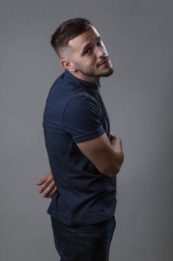 Yan görünümü erkek elleri arkadan giyer rahat kıyafetler, izole gri arka plan üzerinde. Çekici olumlu adamın yüzü neşeli ifade yok