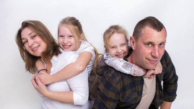 Gri arka plan üzerinde gülümseyerek mutlu bir aile portresi. İki çocuk kızı, Baba, gülen ve sarılma anne. Aile tatili ve beraberlik.