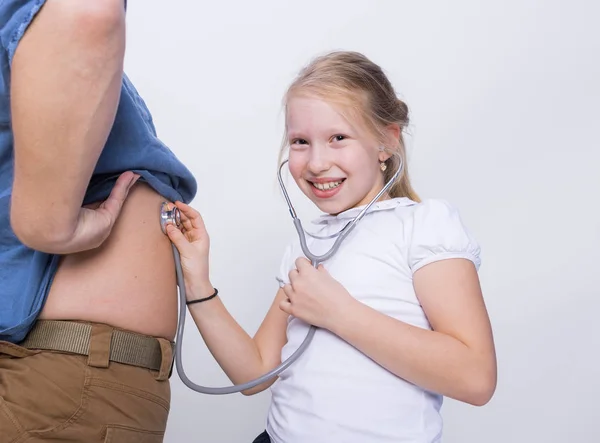 Father and daughter playing in doctor with a stethoscope on a gray background. Medical examination father\'s day concept.