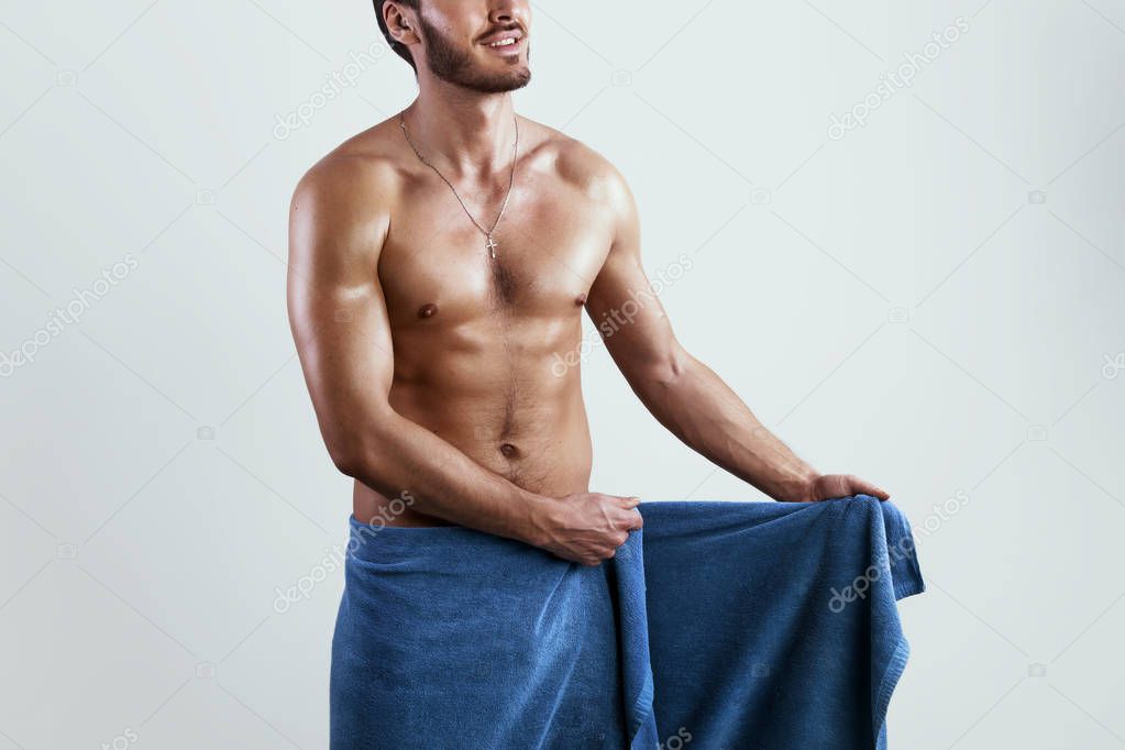 Wet sexy torso men wrapped in the blue towel isolated on grey background