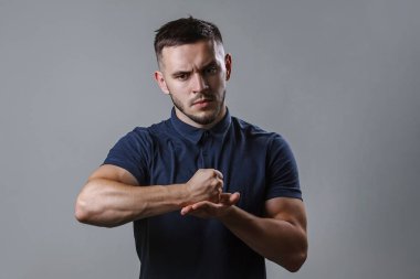 Genç ciddi bir adam portresi kapatın. Yakışıklı karanlık gömlek gri arka plan kopya alanı üzerinde duran avucunun yumruk vurmak