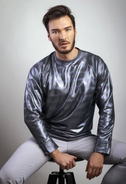 Ücretsiz ve onun tarzı rahat hissediyor. Gümüş raglan kamera bir sandalyede otururken bakan güzel yakışıklı adam. Tiyatro ve duygular