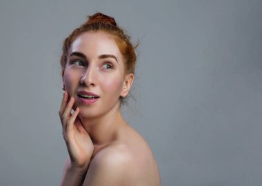 Portre genç Kızıl saçlı ve yeşil gözler güzel yarı çıplak kadın ile temiz cilt dokunmatik kendi yüz. Yüz tedavi. Kozmetik, güzellik ve spa .