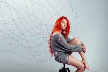 Portre Kızıl saçlı kız dağınık örgü kazak ve çıplak bacaklar giymiş. Konu gibi bir kazak gevşemek ve delik bırakarak kanatlar, çekti.