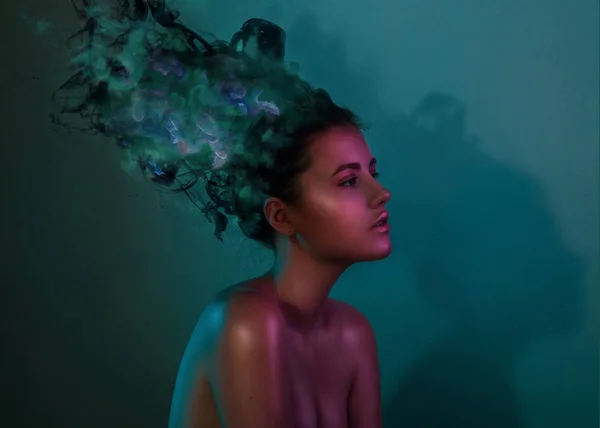 Modetrend Porträt eines jungen Mädchens im Studio mit rauchfarbener Tinte anstelle von Haaren. helle Gele Filter. Mädchen Glanz Gesicht in blauer und lila Farbe Licht auf dunkelblauem Hintergrund — Stockfoto