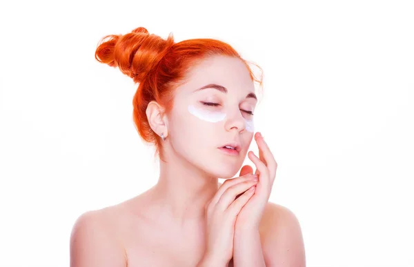 Portrait of a young teen red hair and green eyes girl with clean fresh skin touch own face applying face cream. Facial treatment. Cosmetology , beauty and spa isolated on white background — Stock Photo, Image