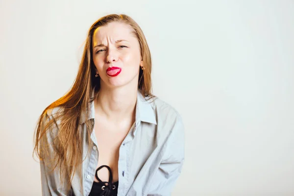 Making faces, tongue out, Woman portrait. Fun. Cheerful young woman is grimacing and showing her tongue at camera, on a gray background. Human emotion facial expression body language. — Stock Photo, Image