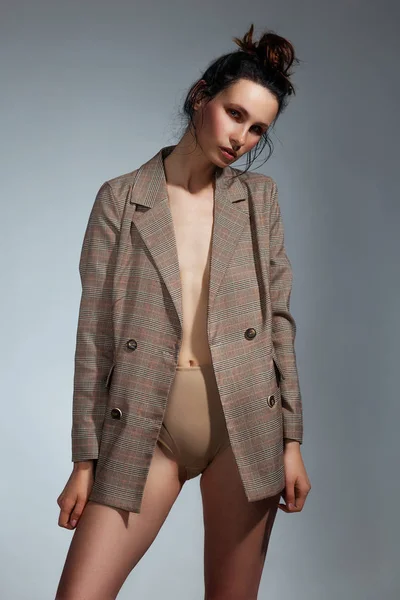 彼女の裸の体の上にジャケットを着てかわいいブルネットの女性とスタジオのファッションと美しさのコンセプトでポーズハイウエストの下着 — ストック写真