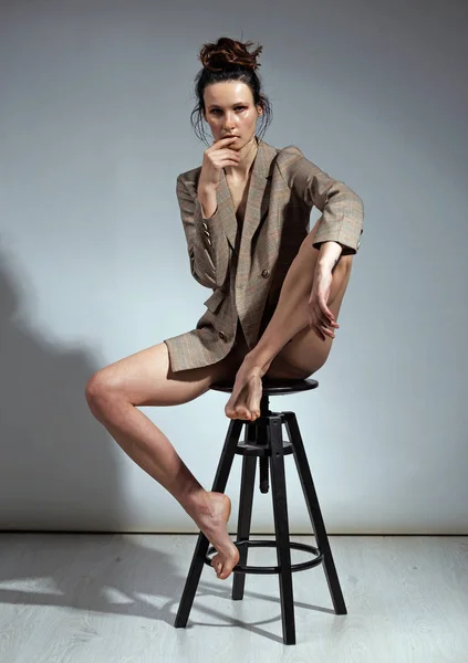 Roztomilá brunetka, která nosí kabát přes své nahé tělo a vysoké spodní prádlo Pózované ve studiovém módu a konceptu krásy — Stock fotografie