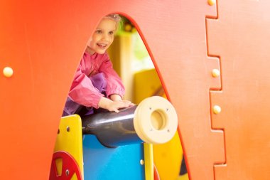 Aktif küçük kız oyun üzerinde küçük bir evde gülümseyen