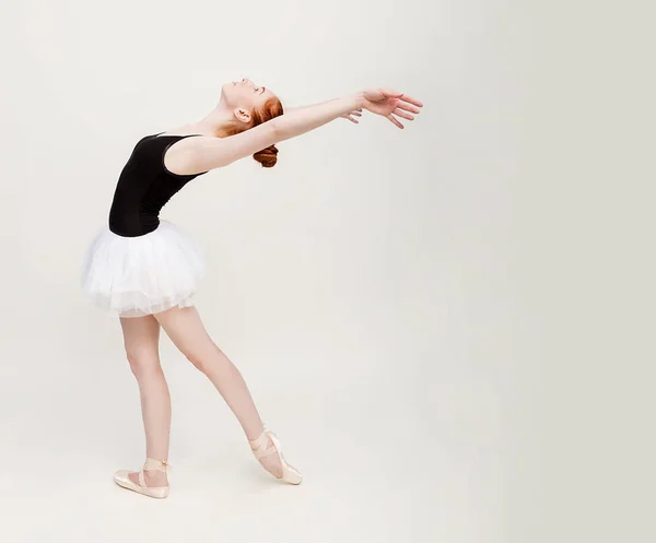 Jovem e incrivelmente bela bailarina está posando e dançando em um estúdio cinza claro cheio de luz. A foto reflete muito a beleza incomparável de uma arte clássica de balé. Espaço de cópia — Fotografia de Stock