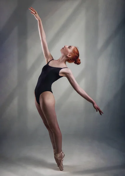 Jonge en ongelooflijk mooie ballerina is poseren en dansen in een licht grijze Studio volledige hoogte. De foto weerspiegelt sterk de onvergelijkbare schoonheid van een klassieke ballet kunst. — Stockfoto