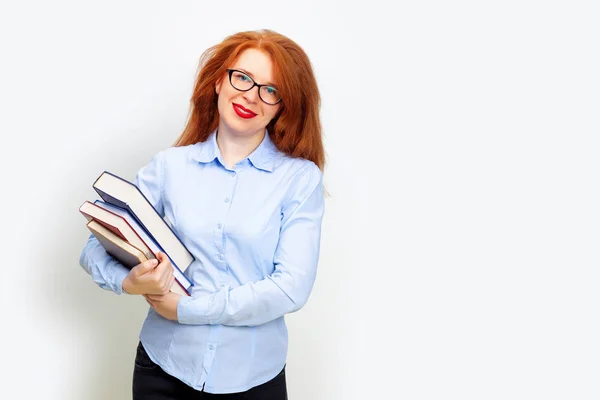 Begreppet utbildning, rödhårig kvinna med glasögon rymmer en bunt med många böcker olika färger i händerna. Känslor ansiktsuttryck. Isolerad på vit bakgrund, kopiera utrymme — Stockfoto