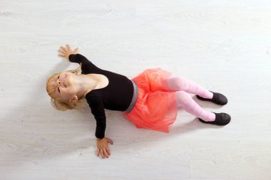 Pembe etekli küçük dansçı kız. Anaokulu çocuğu ahşap zeminde oturuyor. Beyaz stüdyoda klasik bale yapan şirin bir çocuk. Çocuklar dans eder. Sınıfta genç bir dansçı. Metnin için boşluk kopyala