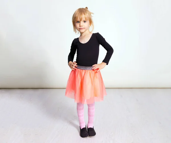 Menina bailarina loira posando no clube de dança com piso de madeira e parede branca. Jovem dançarina de balé em tutu rosa, se divertindo e sorrindo. Fundo, espaço de cópia . — Fotografia de Stock