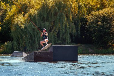 Wakeboard kullanan bir kadın. Dalgaları keser ve bir yaz gölünde su sıçratır