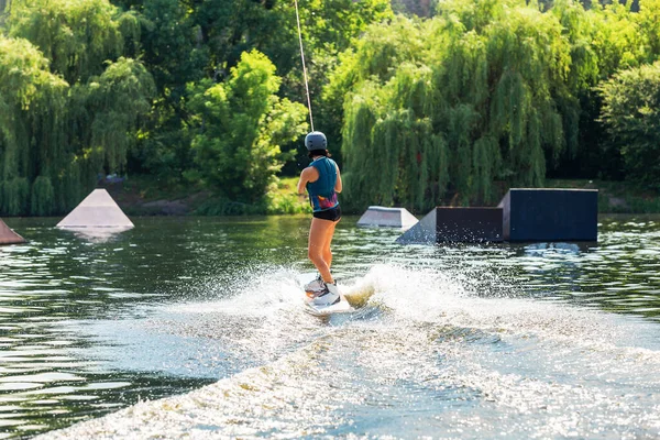 女性はウェイクボードに乗る 夏の湖で波を切り スプラッシュを発生させる — ストック写真