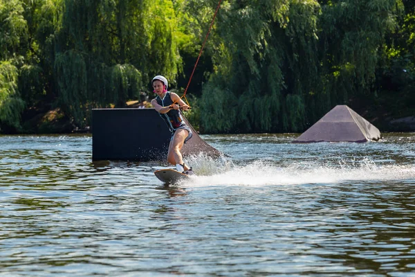 女性はウェイクボードに乗る 夏の湖で波を切り スプラッシュを発生させる — ストック写真