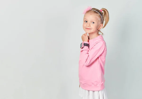 かわいい白人の女の子4 5歳は彼女の手首にスマートウォッチを身に着けています グレーのスタジオを背景にした子供のための技術 — ストック写真