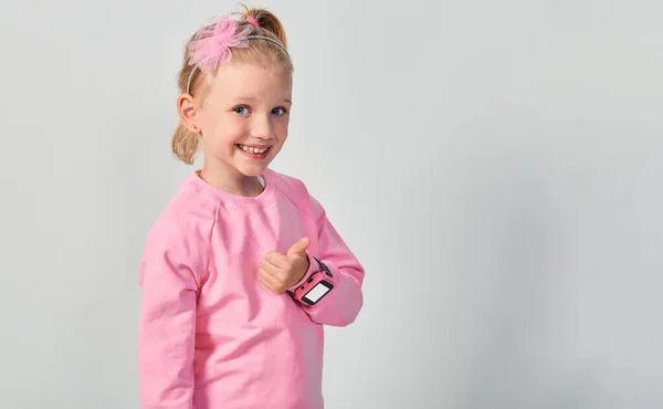 かわいい白人の女の子4 5歳は彼女の手首にスマートウォッチを身に着けています グレーのスタジオを背景にした子供のための技術 — ストック写真