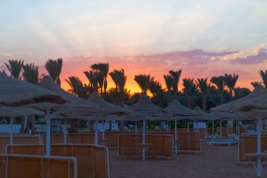 Boş güneşlikler ve batan güneşli doğal şemsiyeler.