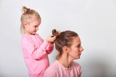4-5 yaşındaki küçük kız annesinin saçını yapıyor. Pembe giysiler içinde birlikte vakit geçirmeyi seviyorum.