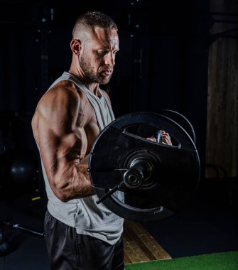 Ağırlıklarla antrenman yapan kaslı adam. Güçlü atletik adam egzersiz yapar. Vücut geliştirme uzmanı spor salonunda egzersiz yapıyor..