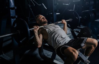 Ağırlıklarla antrenman yapan kaslı adam. Güçlü atletik adam egzersiz yapar. Vücut geliştirme uzmanı spor salonunda egzersiz yapıyor..