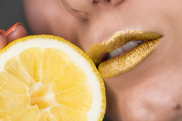 Mooie close-up met vrouwelijke lippen met gouden kleur make-up en citroen slice. Glitter cosmetica — Stockfoto