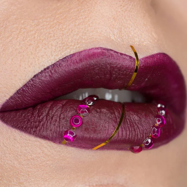 Крупним планом вид красивих жіночих губ з винною фіолетовою матовою помадою. Косметологія, модний макіяж. Ювелірні вироби на губах — стокове фото