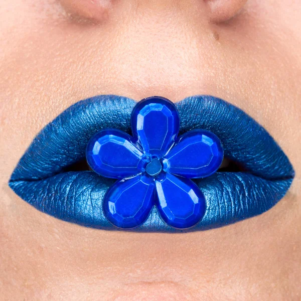 Närbild syn på vackra kvinnan läppar med blått läppstift. Sluten mun. Kosmetika, mode makeup. Smycke blomma — Stockfoto
