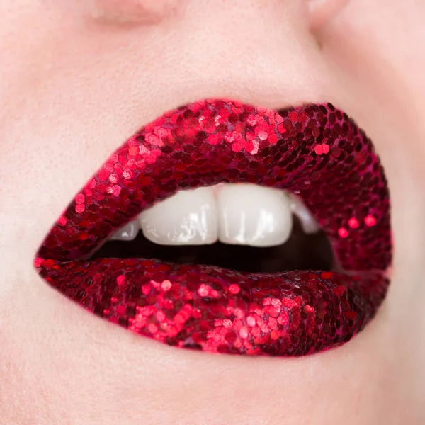 Red lips covered with sparkles. Beautiful woman with red lipstick on her lips, open mouth, concept cosmetics