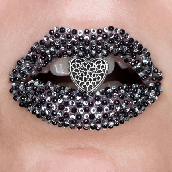 Macro e close-up criativo make-up belos lábios femininos com pedras preciosas pretas e prateadas e coração na boca aberta — Fotografia de Stock