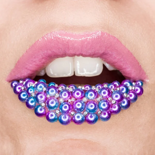 Close-up de mulheres belos lábios sexy com batom rosa e pérolas azuis e rosa em lábios, cosméticos, maquiagem, arte labial — Fotografia de Stock