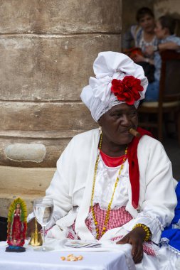 Havana, Küba - 29 Ocak 2018: Sokakta kırmızı kartlı geleneksel kıyafetler giyen purolu kadının portresi