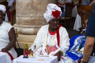 Havana, Küba - 29 Ocak 2018: Sokakta oturan purolu kadın, kırmızı kartlı geleneksel kıyafetler giyiyor