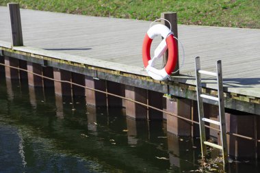 Güneşli bir günde şehrin göl kenarındaki merdivenlerin yanındaki su birikintisi kurtarma çemberi.