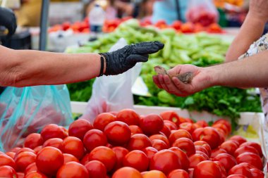 Kadın adam sokak pazarından taze organik meyve ve sebze alıyor. Plastik torbada meyve satmak, para ödemek..