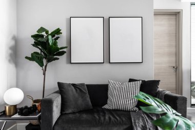 Yumuşak yastıklar ve duvarda boş çerçeveler ile rahat gri kadife kanepe 