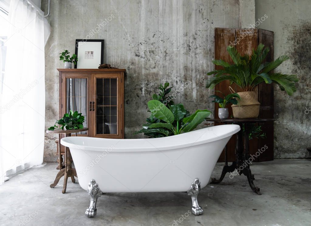 stylish bathroom interior with classic bath and artificial plants as decorations 