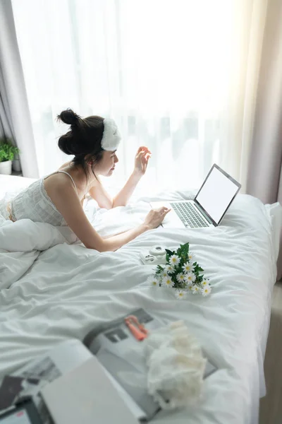 Ženy pokládání na lůžko při práci s laptopem ráno — Stock fotografie