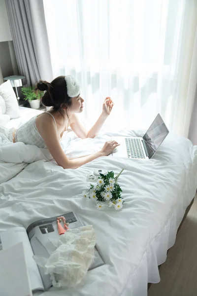 Donne sdraiate sul letto mentre lavorano con il computer portatile al mattino — Foto Stock