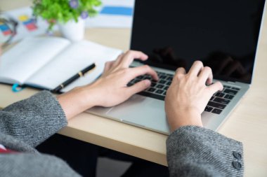 İş adamı, ahşap masa üzerinde ofis aksesuarları olan bir dizüstü bilgisayarda bilgi yazarken. İş ve teknoloji kavramı / Kopyalama alanı