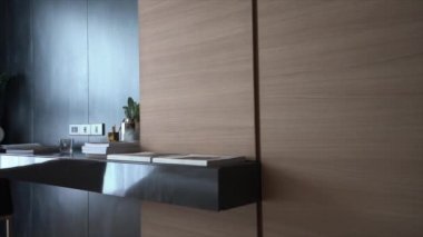 Çalışma köşesinde kitaplarla dekore edilmiş beyaz mumlar ve siyah ahşap çalışma masasının üzerinde cam vazoda suni bitki arka planda metal duvar / apartman içi / fotokopi alanı