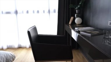 Çalışma köşesinde kitaplarla dekore edilmiş beyaz mumlar ve siyah ahşap çalışma masasının üzerinde cam vazoda suni bitki arka planda metal duvar / apartman içi / fotokopi alanı