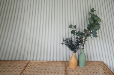 Seramik vazolardaki güzel yapay bitkiler boş rattan bank üzerine kurulmuş, beyaz kıvrımlı duvar, minimal modern stil daire / konut iç konsepti / kopyalama alanı içeriyor.