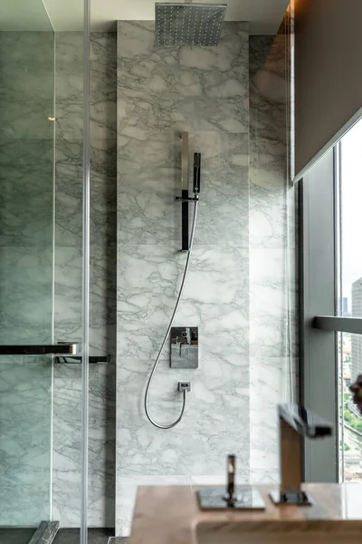 Modern bathroom interior with stainless steel shower set and  white natural marble wall / interior design / copy space