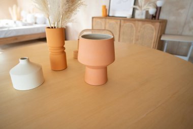 Yatak odası çalışma odası köşesi renkli seramik vazo ve yapay bitki ile dekore edilmiş doğal ahşap çalışma masasının üzerinde arka planda / apartmanın içinde güzel bir iç mekan / kopyalama alanı var.