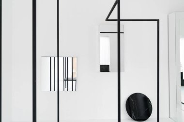 Soyut dairesel mermer ve metal çizgileri olan minimal siyah ve beyaz oda, doğal ışık ayarı sahnesinde aynaya yansıyor.